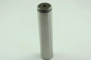 A cylindrical metal object stands upright against a plain white background. It has a smooth surface with a darkened top, appearing solid and industrial in design.