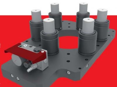 Ein 3D-gerendertes Bild einer grauen Industriekomponente mit sechs zylindrischen Strukturen auf der Oberseite und einem roten Hebelmechanismus an einer Seite. Der Hintergrund ist durchgehend rot.