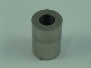 A cylindrical metal bushing with a hollow center, standing upright on a light surface.