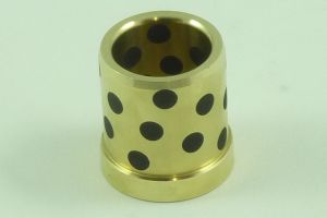 A cylindrical brass bushing with evenly spaced black dots on its surface, set against a plain light green background.